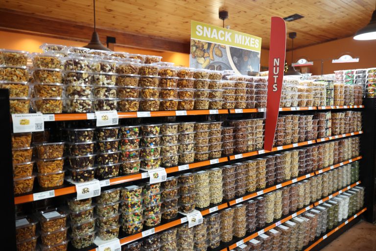 Variety of snack mixes displayed neatly, bulk food items. shop online or in store