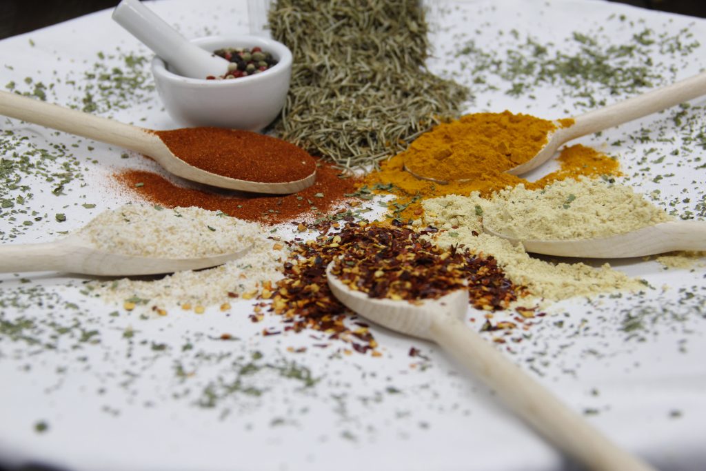 Colorful seasonings on spoons and sprinkled on the table
