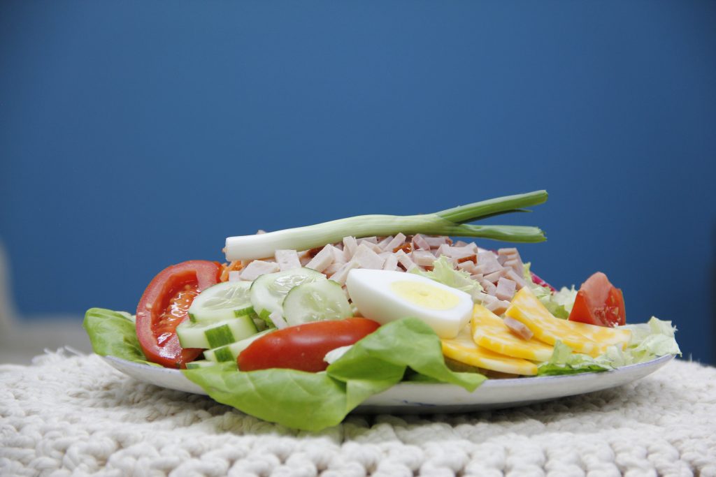 Delicious salad with lettuce, cucumbers, ham, cheese, tomatoes, and more